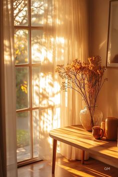 a table with vases and flowers on it in front of a window that has the sun shining through