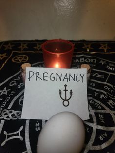 a candle sitting on top of a table next to a paper with the word pregnancy written on it