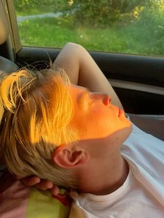 a young boy laying in the back seat of a car with his head up on someone's shoulder