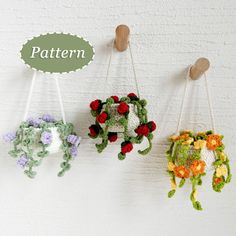 three crocheted flowers hanging from hooks on a wall with the words pattern above them