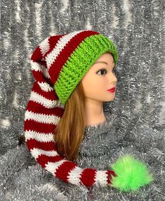 a mannequin head wearing a green and red striped hat with pom - pom