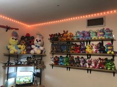 there are many stuffed animals on the shelves in this room with lights strung above them