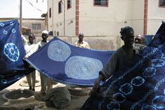 several men holding up blue cloths in front of a building with other people around them