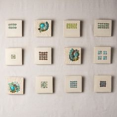 nine ceramic tiles arranged on a wall with beaded designs and beads in the middle