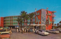 people are standing in front of a red and green building with cars parked on the street