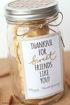 a glass jar filled with cookies on top of a wooden table next to a sign that says, thank for sweet friends like you