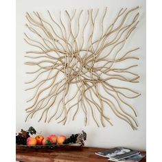 a wall sculpture made out of branches with fruit on the table in front of it