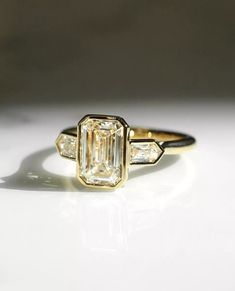 an emerald and diamond ring on a white surface