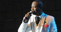 a man in a white suit singing into a microphone