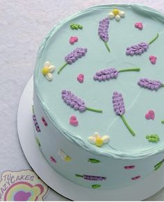 a blue cake with flowers on it sitting on top of a white plate next to a sticker