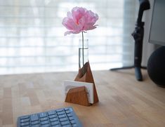 a pink flower in a glass vase next to a keyboard