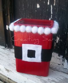 a red and black box with white pom - poms on it sitting on a wooden bench