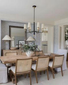 a dining room table with chairs and a vase on top of it in front of a mirror