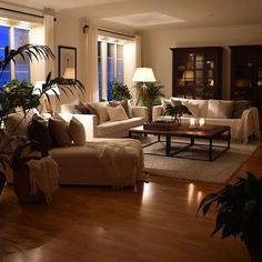 a living room filled with lots of furniture next to large windows and wooden flooring