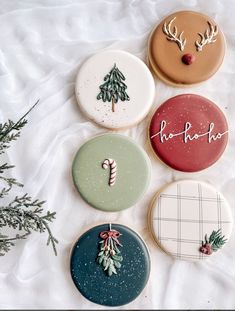 four decorated cookies sitting on top of a white blanket next to a christmas tree and candy cane