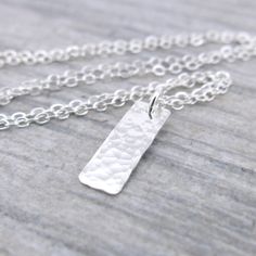 A dainty classic small silver bar necklace. This necklace is specifically created to be just a whisper along your neck line, dainty, delicate, lightweight and beautiful. Perfect for layering with your favorite pieces. Petite and dainty, this necklace consists of a 5/8 inch Sterling Silver rectangle bar, hammered with my Classic texture and suspended from dainty 1.9mm Sterling Silver cable chain. The pendant is suspended just over 5/8 inch in length from the chain and tumble polished for shine. P Simple Sterling Silver Necklace With Rectangular Pendant, Simple Silver Rectangular Pendant Jewelry, Simple Silver Necklace With Rectangular Pendant, Silver Dainty Bar Necklace For Everyday, Dainty Silver Bar Necklace Gift, Silver Minimalist Necklace With Rectangular Pendant, Nickel-free Rectangular Pendant Necklace For Everyday, Elegant Silver Rectangular Bar Necklace, Silver Engraved Rectangular Bar Necklace