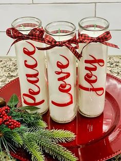 three coca - cola cans sitting on top of a red plate next to evergreen branches