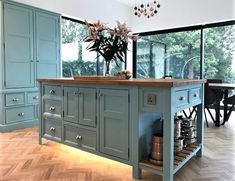 a large kitchen island in the middle of a room with wooden floors and blue cabinets