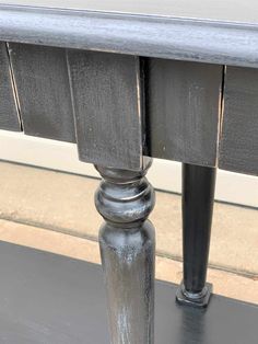 a black table with two metal poles on the top and bottom, in front of a window