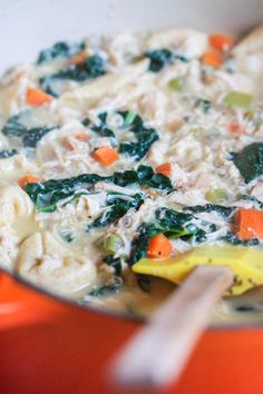 an orange pot filled with pasta and vegetables