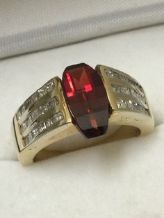 Over 6 carats of fancy cut Spessartite Garnet set in 14kt. yellow gold accented with 48 SI diamonds. One of a kind. This ring has the Wow factor.  You look at it and say Wow! The gem, diamonds and gold are all 100% genuine. The gem sits in a channel setting. The gem has rich saturation and the diamonds sparkle out loud. Perfect engagement or statement ring. Spessartite Garnet, Garnet Gem, Channel Setting, Gem Diamonds, Garnet Ring, Red Band, Diamonds And Gold, Star Ring, Garnet Rings