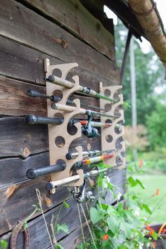 a wooden wall with several different types of pipes attached to it and some flowers in the foreground