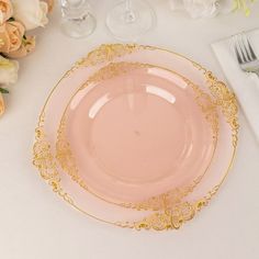 a pink and gold plate sitting on top of a table next to white napkins