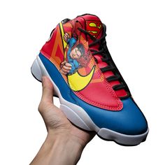 a hand holding up a shoe with superman on it