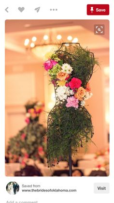 a dress made out of flowers and greenery on a stand in a banquet hall