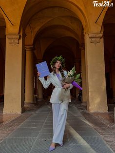 a woman in a white suit is holding flowers