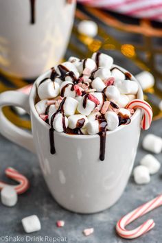 hot chocolate and marshmallows in a white mug with candy canes around it