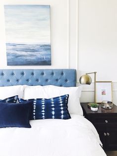 a bed with white sheets and blue pillows