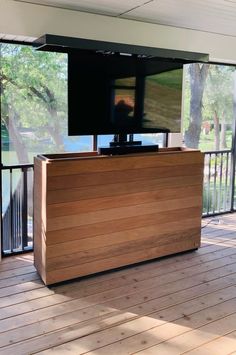 a flat screen tv sitting on top of a wooden stand next to a window with sliding glass doors