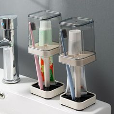 three toothbrushes and two toothpaste holders on a sink