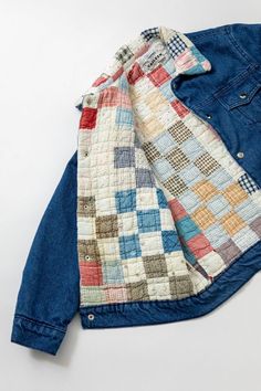 an old jacket is laying on top of a white surface with blue and red colors