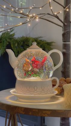 a glass teapot filled with flowers on top of a table