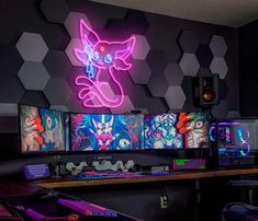 a computer desk topped with lots of computers and neon signs on the wall behind it