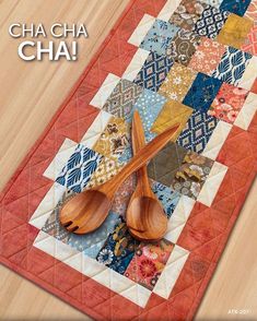 a table runner with two wooden spoons on it and the words cha cha cha