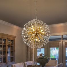 a chandelier hanging from the ceiling in a dining room with chairs and table