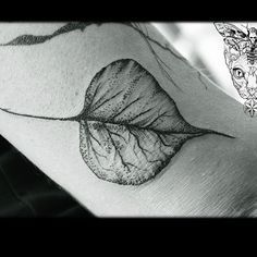 a woman's arm with a leaf tattoo on it