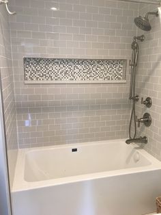 a white bath tub sitting inside of a bathroom next to a shower head and faucet