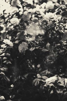 a black and white photo of a person's face surrounded by flowers