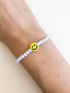 "customize your very own happy smiley face stretchy bracelet, made to order in your size! you will receive one white beaded bracelet with your choice of center smiley bead (gold or yellow). PLEASE NOTE: you will receive ONE bracelet with this order. these super trendy and versatile stretch bracelets are the perfect little accessory for your wrist. they are dainty and beautiful by themselves, but also look great when combined and stacked. you can add to your stack right here: http://www.etsy.com/ White Stretch Bracelet With Smiley Face For Gift, White Bracelets With Smiley Face For Gift, Everyday White Bracelets With Smiley Face, Casual White Friendship Bracelets With Smiley Face, White Smiley Face Bracelet As Gift, Cheerful Adjustable White Beaded Bracelets, Adjustable Cheerful White Beaded Bracelets, Playful White Friendship Bracelets With Smiley Face, Cheerful White Adjustable Beaded Bracelets