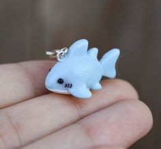 a small blue fish charm sitting on top of a person's finger