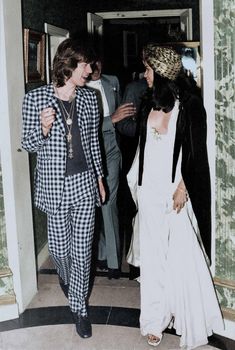 two people walking in an open doorway with one person wearing a black and white checkered suit