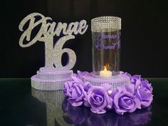 a cake with purple flowers and a candle on it next to a sign that says angel 16