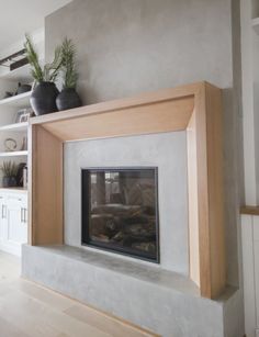 a living room with a fire place and bookshelves on the wall above it