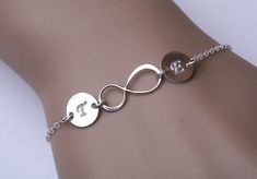 "An original design by TYDesign, this simplistic bracelet with personalized initials consists of: 1. a sterling silver initial infinity charm 2. two sterling silver discs (22ga, 3/8\"; in-line with the infinity charm and the chain) hand-stamped with the loving couple's initials in your choice of font. 3. a sterling silver chain (length customizable) closed with a lobster clasp All components are sterling silver. Packaged in my shop's premium quality gift box (pictured) You can expect the highest Sterling Silver Initials Bracelet For Personalized Gift, Personalized Sterling Silver Initials Bracelet, Sterling Silver Bracelets With Initials For Anniversary, Customizable Silver Name Bracelet For Bridesmaid Gift, Elegant Sterling Silver Name Bracelet For Friendship, Elegant Sterling Silver Friendship Name Bracelet, Silver Name Bracelet With Initials For Wedding, Personalized Infinity Sterling Silver Bracelet, Personalized Sterling Silver Infinity Bracelet