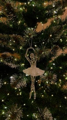 a christmas tree with a ballerina ornament hanging from it's branches