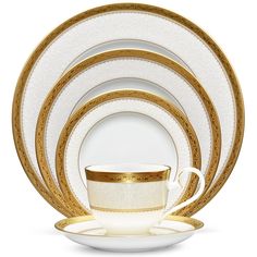 white and gold dinnerware set with golden trimmings on the rim, in front of a white background